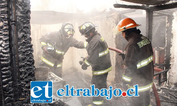 Bomberos en plena acción remojando el terreno tras controlar el incendio.