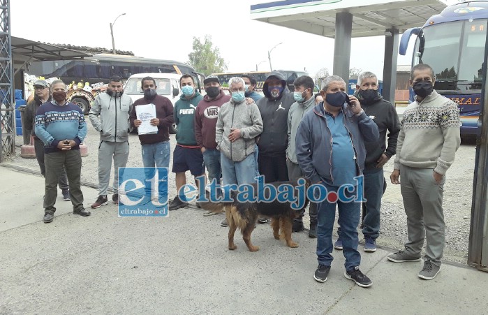 Los trabajadores, afuera del taller, mientras uno de ellos habla por teléfono con la administración de San Felipe.