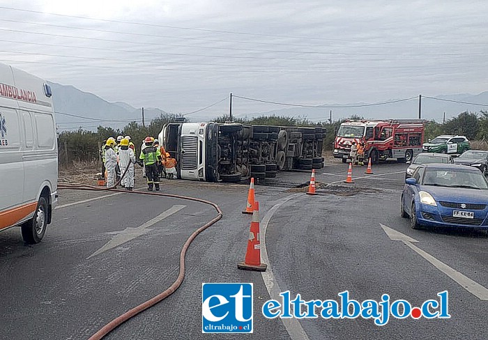 El camión volcado y personal de Carabineros, Bomberos, Haz Mat, trabajando en el lugar.