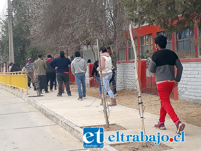 Una larga fila de apoderados esperando afuera de la escuela John Kennedy para retirar a sus hijos o hijas.