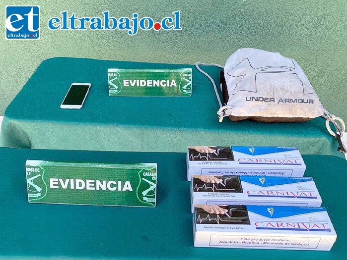 El bolso deportivo y celular recuperados por Carabineros junto a los cartones de cigarrillos de contrabando incautados a los imputados.