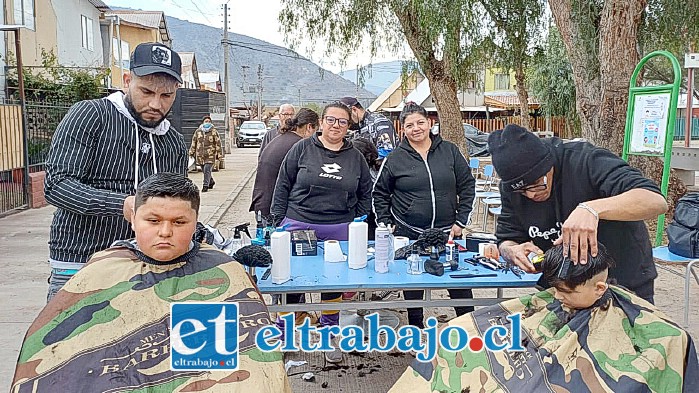 Al medio, de izquierda a derecha, Macarena Astorga, presidenta, y Sandra Díaz, secretaria; al costado un lolito serio mientras le cortan el pelo, en tanto a la derecha el barbero metiendo tijeras.