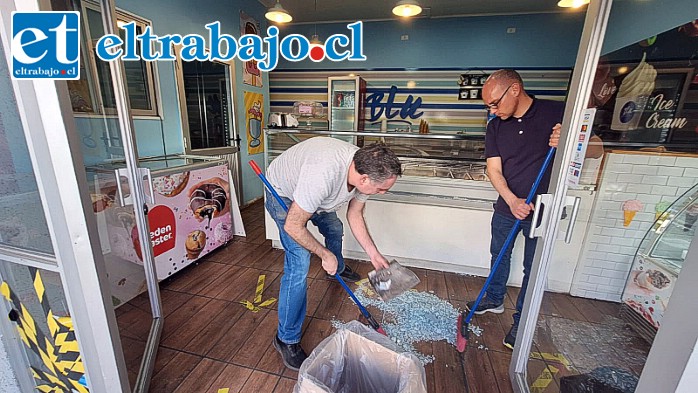 Trabajadores limpiando los múltiples vidrios que dejó el daño a la máquina de exhibición de helados.