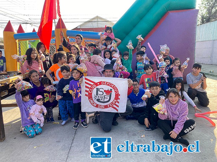 Víctor Escobar, representante de actividades de la barra de Unión San Felipe, sosteniendo la bandera del club, junto a niños y niñas con su bolsita de dulces.