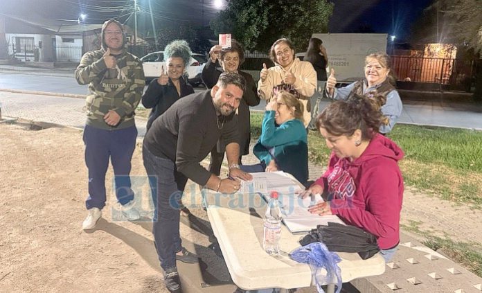 Guillermo Brito sonríe tras firmar la papeleta como candidato, mientras es acompañado de vecinos.