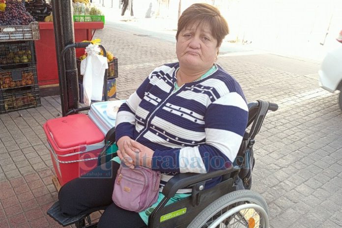 La vecina Rosa Pino Saá en su silla de ruedas, al lado de su cooler con humitas y pasteles de choclo.
