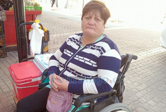 Rosa Pino Saá en su silla de ruedas, su cooler al lado con humitas y pasteles de choclos.