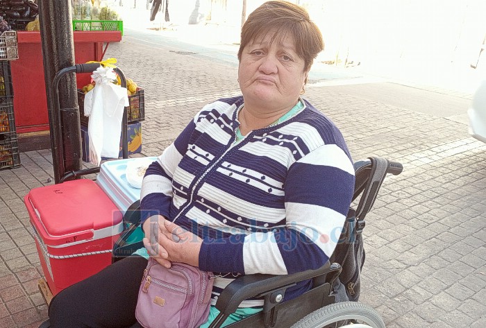 Rosa Pino Saá en su silla de ruedas, su cooler al lado con humitas y pasteles de choclos.