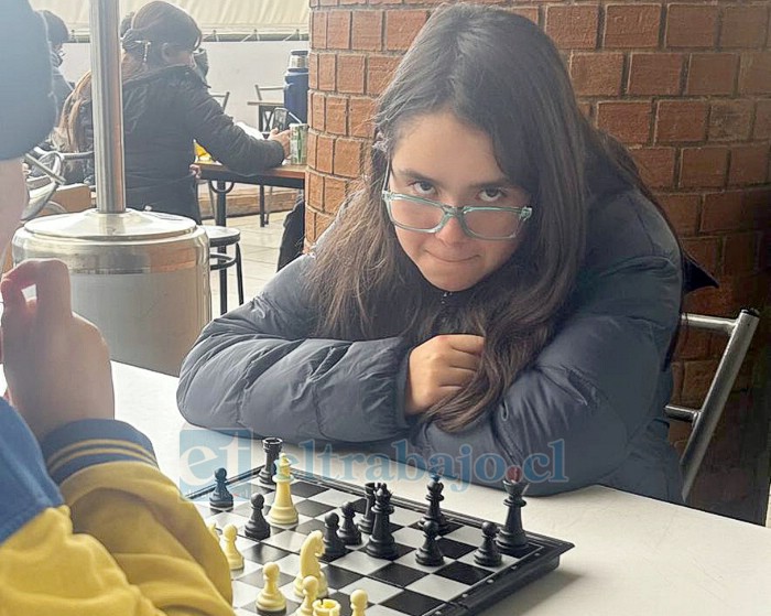 Laura jugando ajedrez aprovecha de mirar a la cámara.